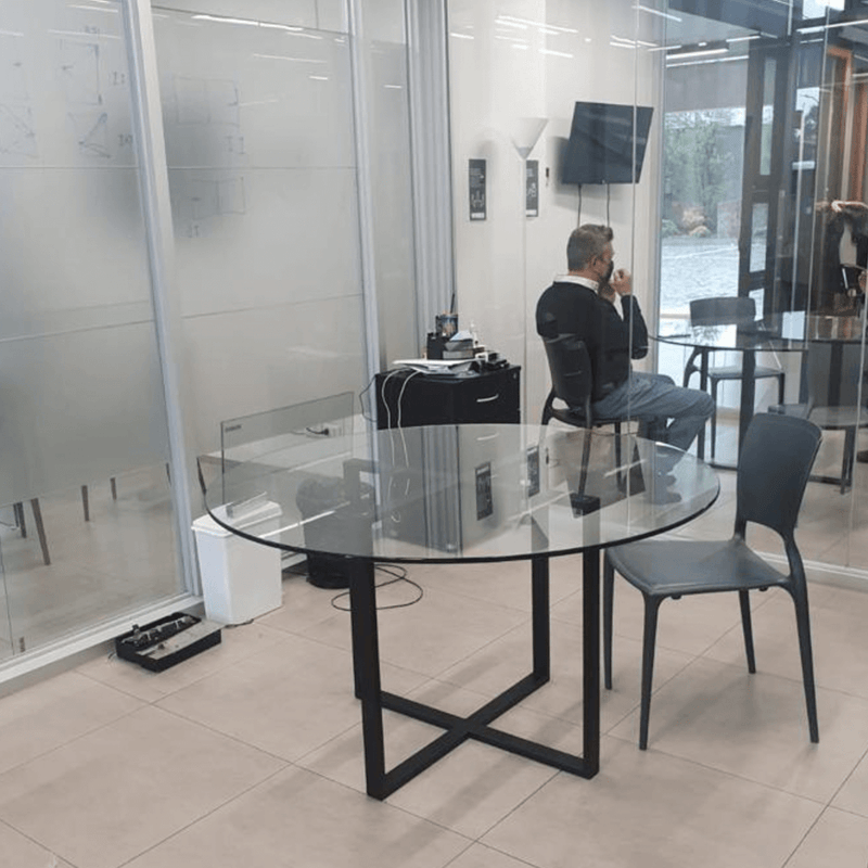 Mesa redonda de vidrio con base de metal en una oficina