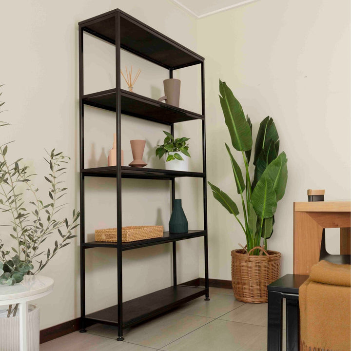Estantería de acero negro con cubiertas de madera teñida negra, en un rincón con plantas y un macetero