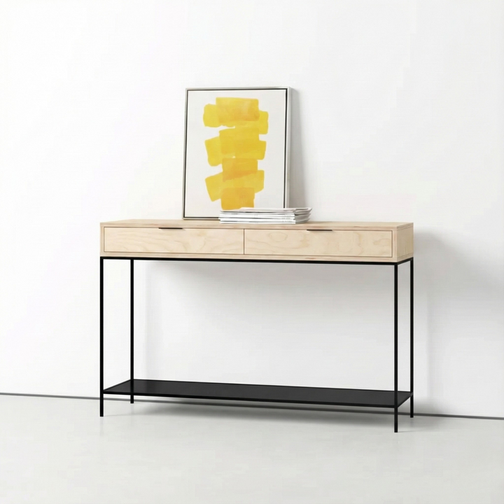 Arrimo con cajonera de plywood de abedul natural y base de metal negro, con un cuadro apoyado