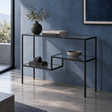 Arrimo de metal negro con cubierta y repisas de vidrio, en un recibidor de muro azul