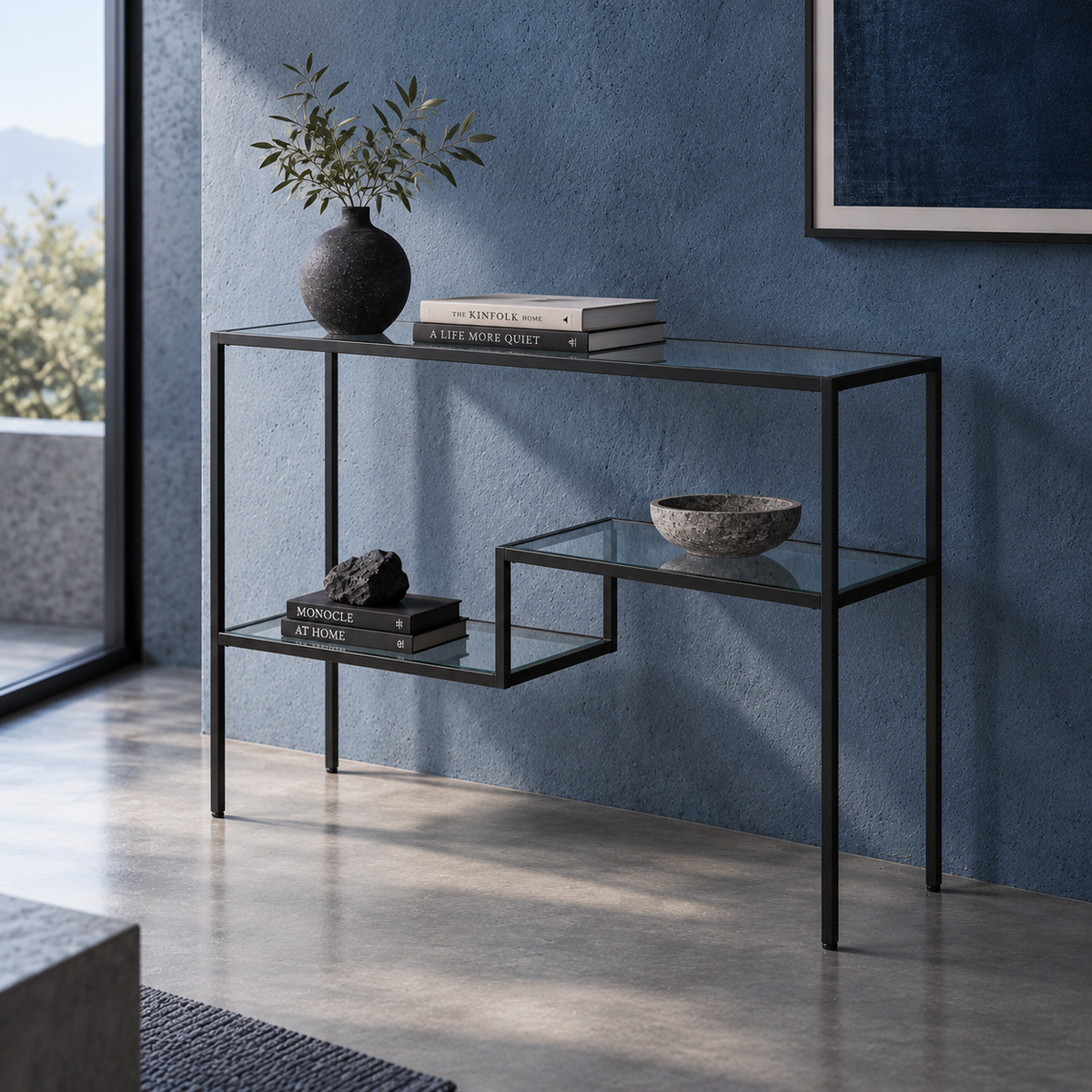Arrimo de metal negro con cubierta y repisas de vidrio, en un recibidor de muro azul