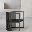Silla individual de acero perforado negro con asiento acolchado, en una sala de muros de hormigón