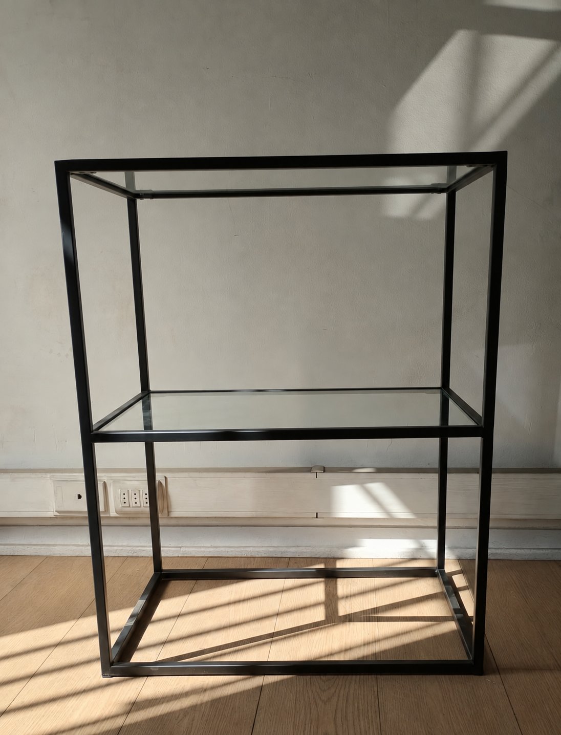 Repisa de dos niveles con estructura de metal negro y bandejas de vidrio, vista de frente