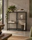 Estantería baja de metal negro con repisas de madera clara, en un living de muro de hormigón