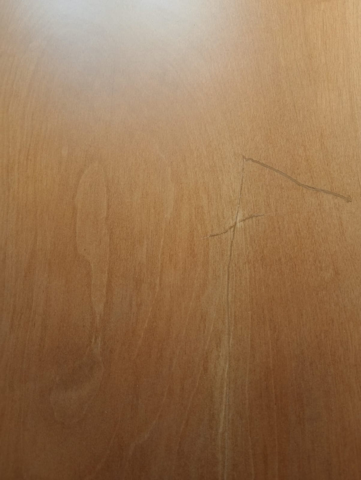 Detalle de la cubierta de madera del velador, con rayas superficiales en el barniz