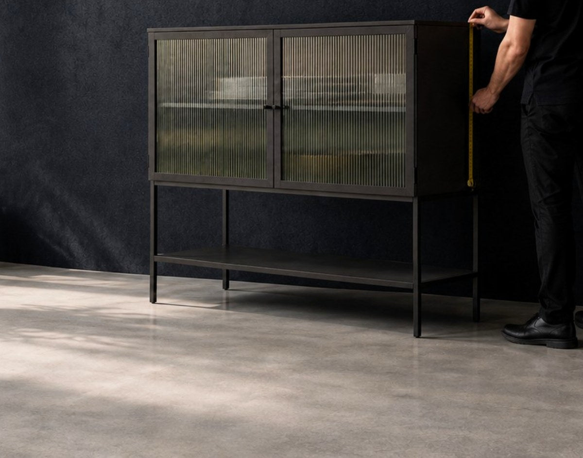 Persona midiendo un mueble de metal con puertas de vidrio