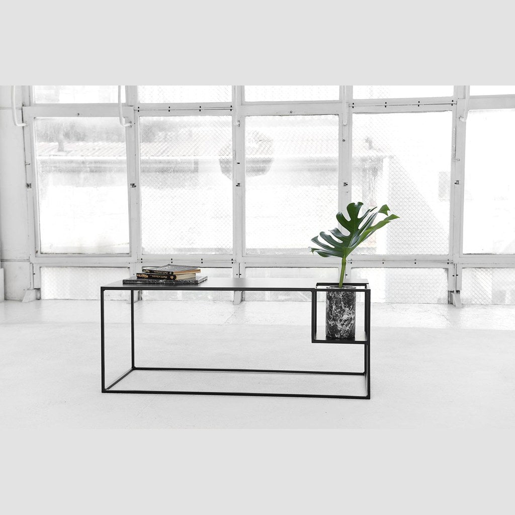 Mesa consola Object 007 Kallfü negra en un loft junto a un ventanal, con libros y planta
