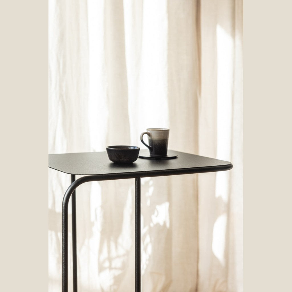 Mesa lateral Denya Kallfü metal negro, cubierta con taza y bowl — en uso