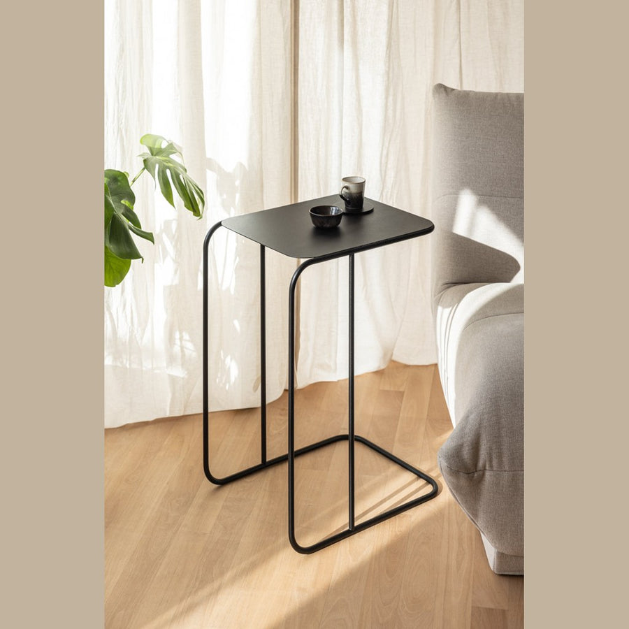 Mesa lateral Denya Kallfü metal negro, 44x35x60 cm — vista 3/4 junto al sofá